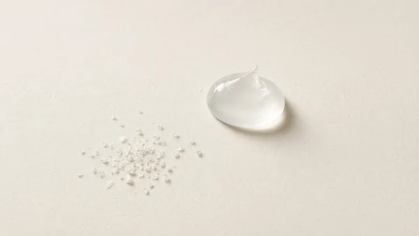 A small mound of fine white powder beside a clear gel swatch on cream paper
