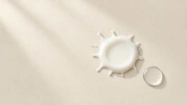 A splash of milky liquid beside a clear droplet