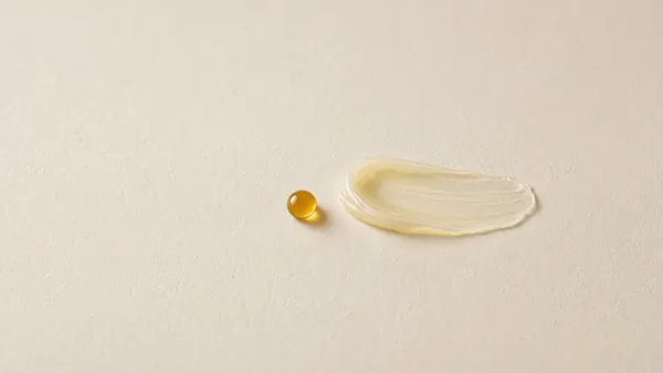 A small amber capsule-like drop beside a pale yellow serum swatch