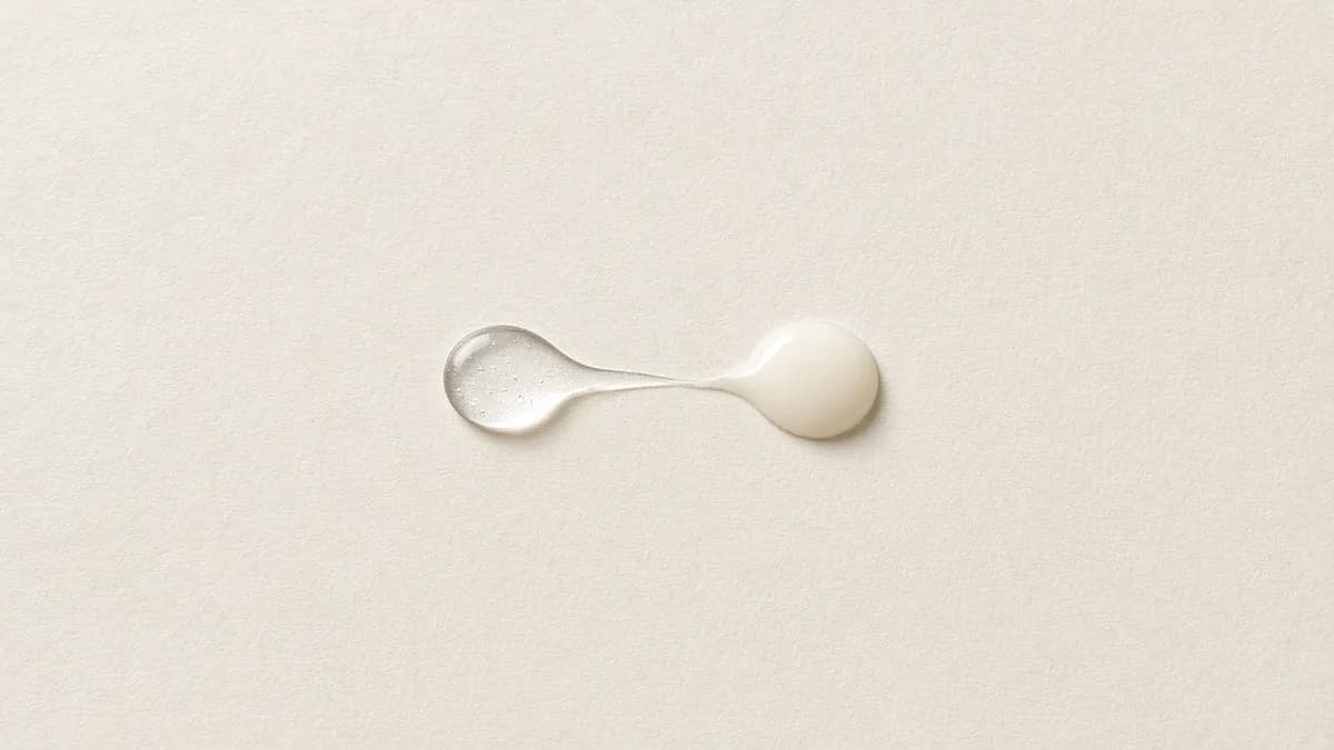 A clear serum drop and a milky ivory drop joined by a thin trail