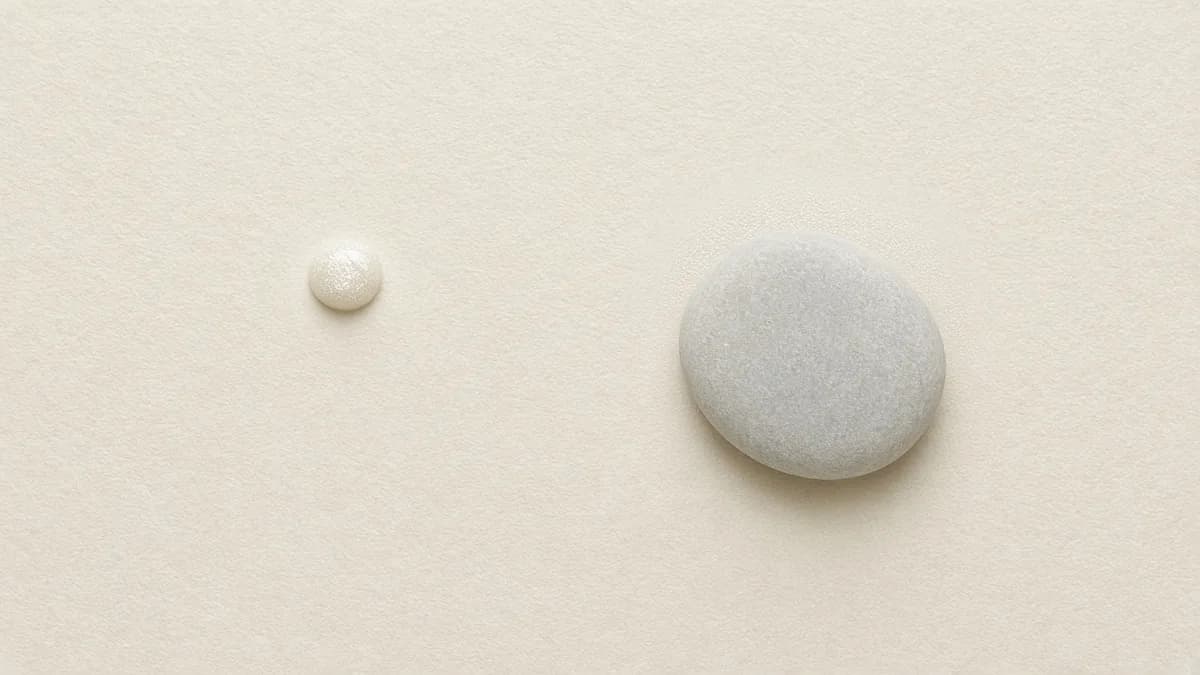 A tiny pearl of eye cream beside a smooth pale grey stone