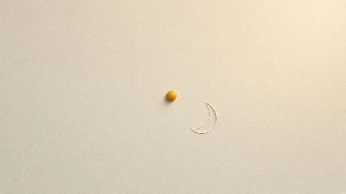 A single small amber drop with a faint swipe of serum on cream paper